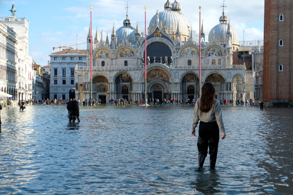  People walk in the flooded St Mark's Square in Venice, Italy