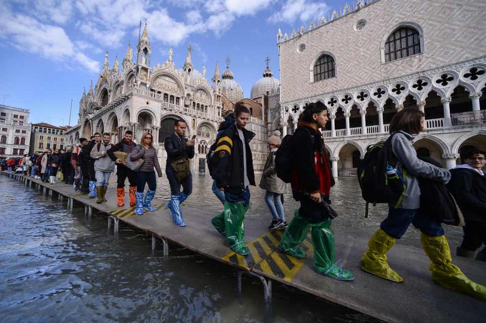  Tourists with water-proofing on their feet march through the flooded lagoon city