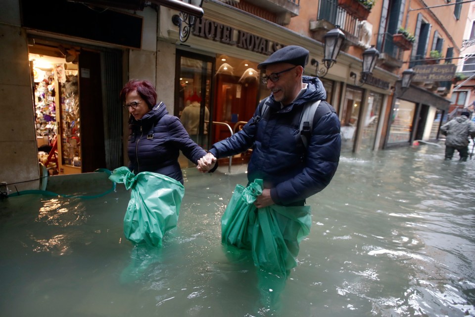  Residents with water-proofing on their feet march through the flooded lagoon city