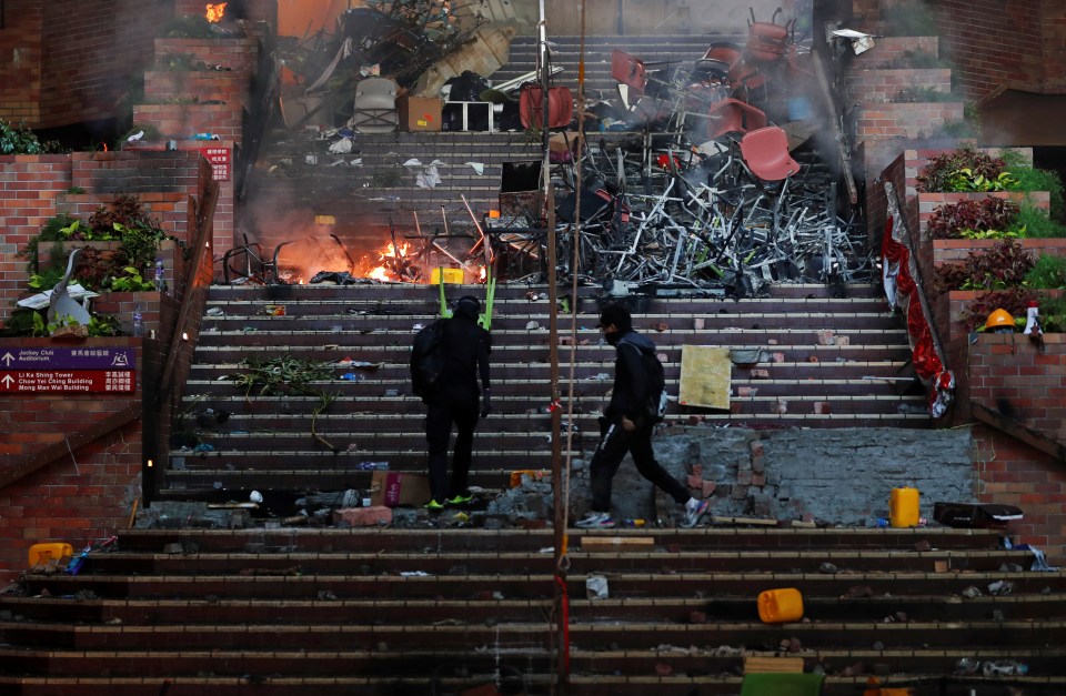 Protesters climb a stairway filled with a makeshift barricade of chairs and other debris outside the university