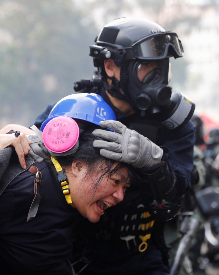 A protester is detained by riot police while attempting to leave the campus