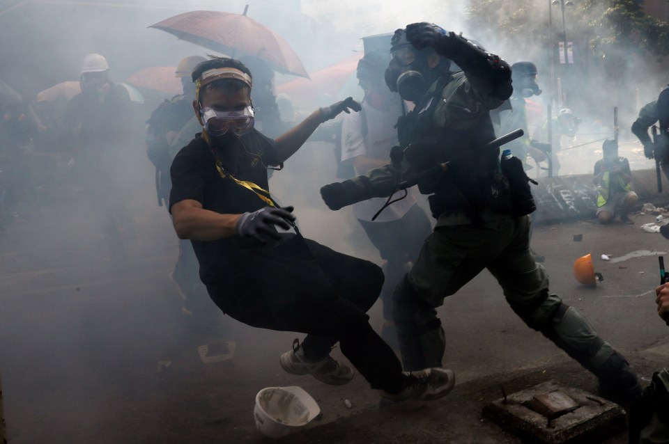 A protester is detained by riot police while attempting to leave the university campus