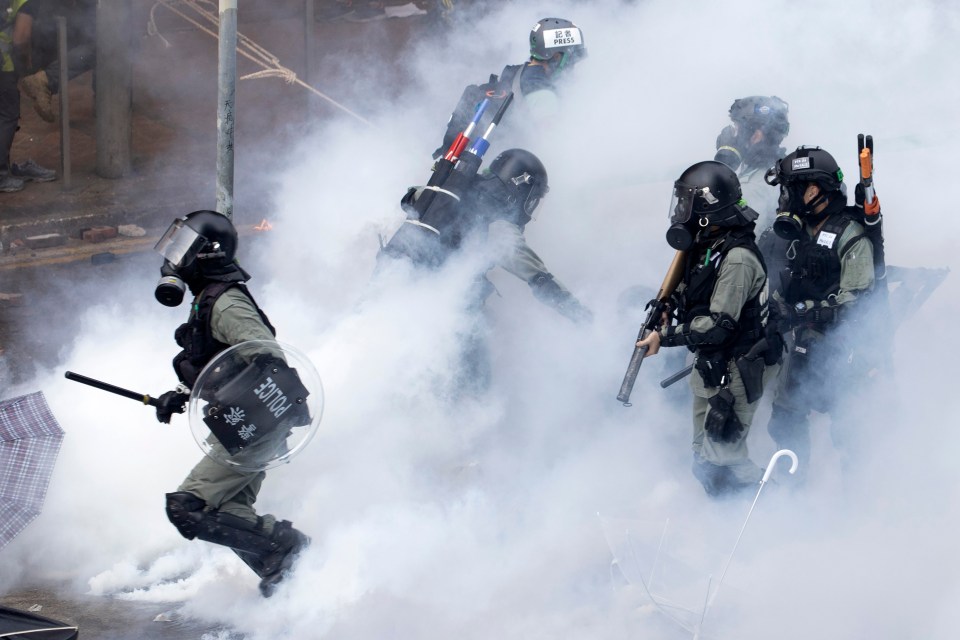 Police in riot gear move through a cloud of smoke at the Hong Kong Polytechnic University