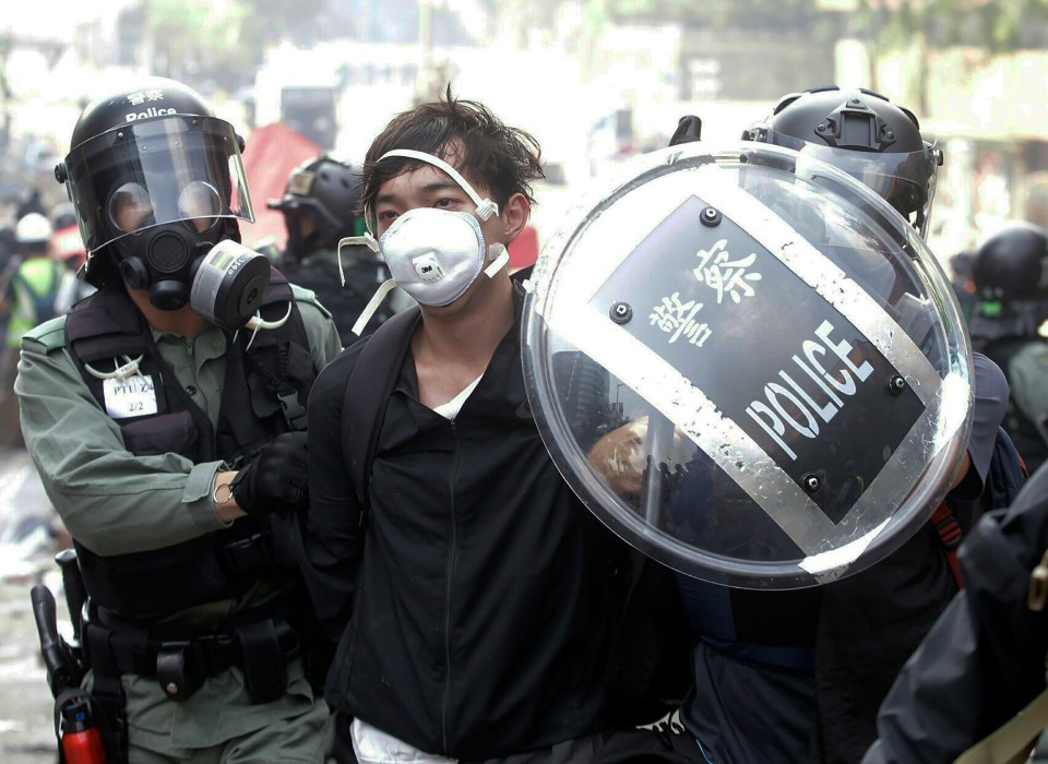 A protester flanked by cops is marched away