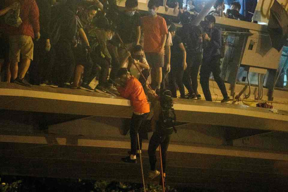  Two protesters bravely lower themselves down with a rope from a bridge to a highway to get away from police