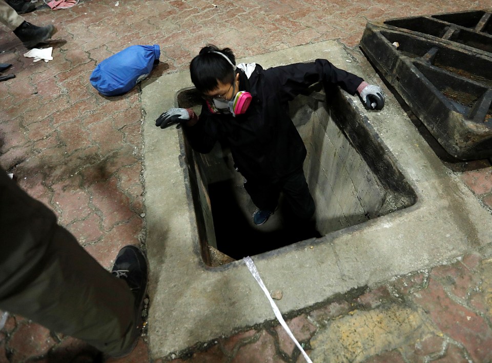  A protester pushes themselves out of the sewer opening to escape from the university