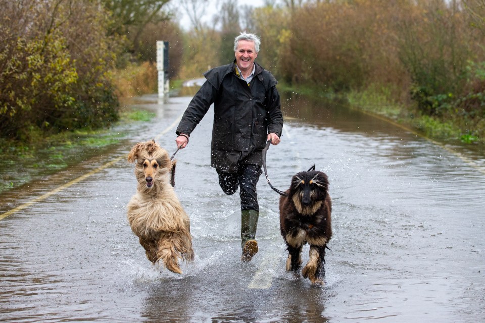 Mike Smith walks is dogs a run on flooded roads in Welney on the Norfolk