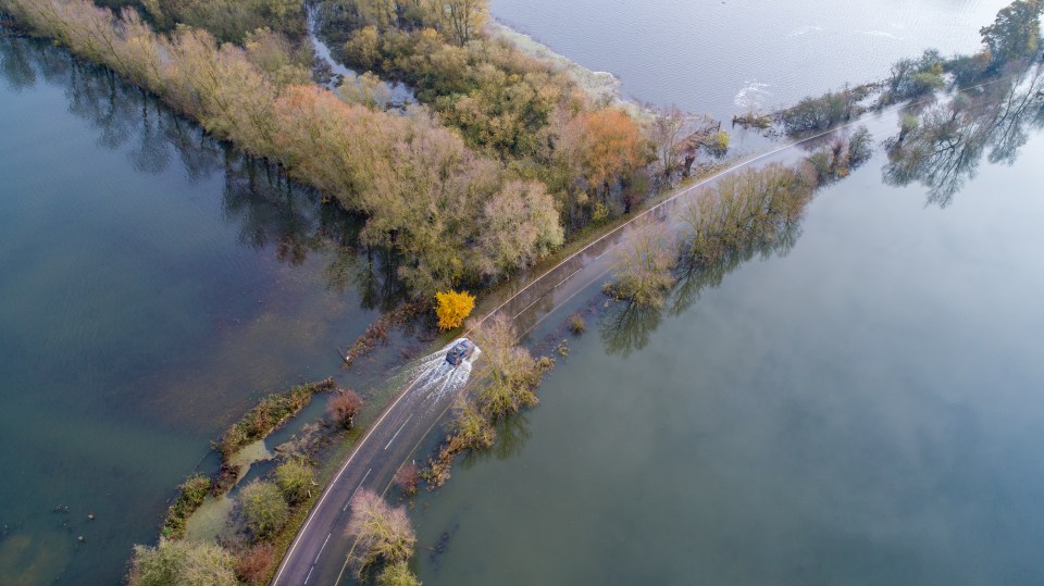 Motorists drive through flooded roads in Welney on the Norfolk