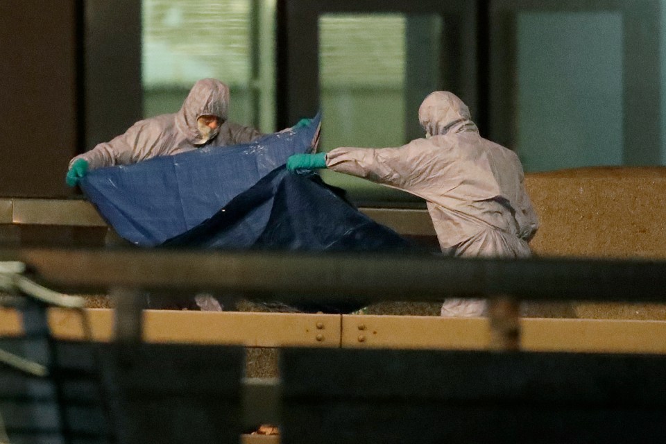  Forensic officers are seen with a large blue tarp on the bridge