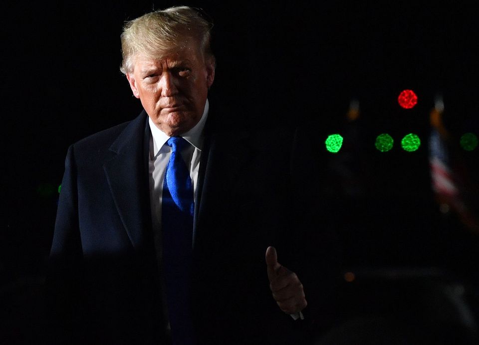  The US President gestures while greeting officials at Stansted Airport, northeast of London