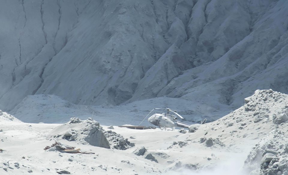  A helicopter is seen on the island covered in ash