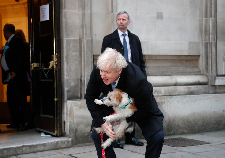 Boris Johnson holds his dog Dilyn as he leaves his polling station