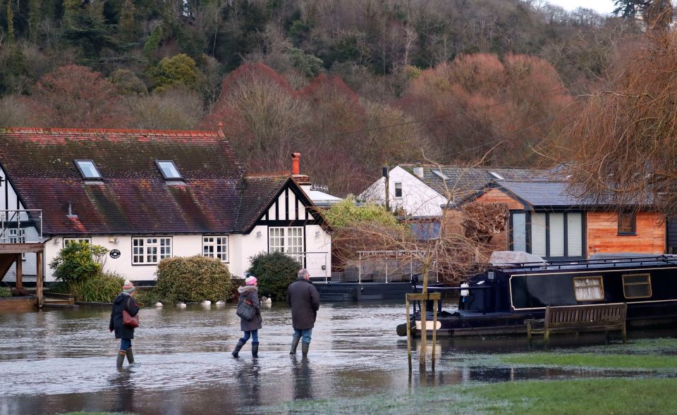 Walkers wade along a flooded towpath in Henley-on-Thames, Oxfordshire