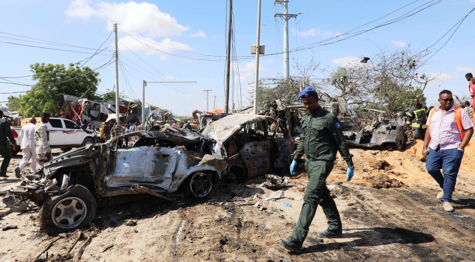  A Somali cop walks past wreckage at the scene of a car bomb explosion in Mogadishu