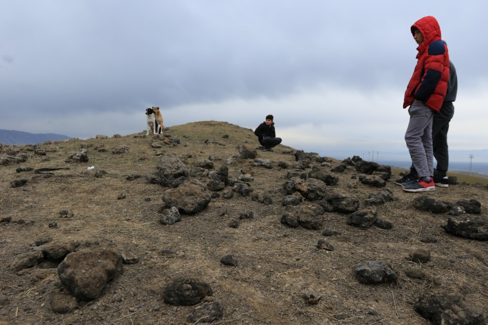  Residents look at a crater caused by a missile on the outskirts of Duhok, Iraq