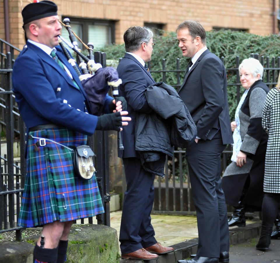  A man plays the bagpipes at the Glasgow funeral