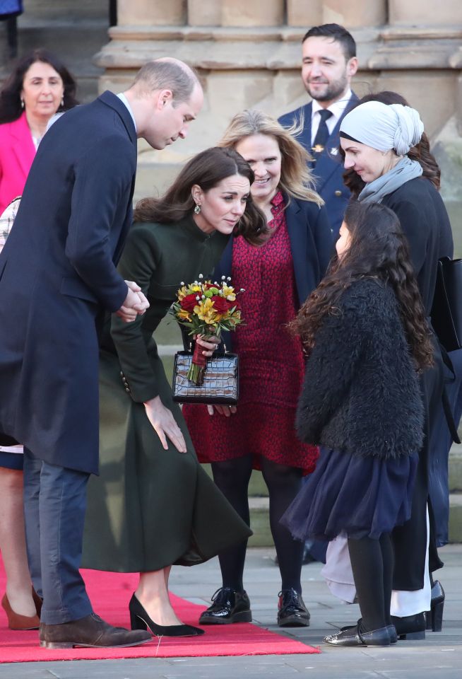  The Duchess of Cambridge bends down as she receives some flowers