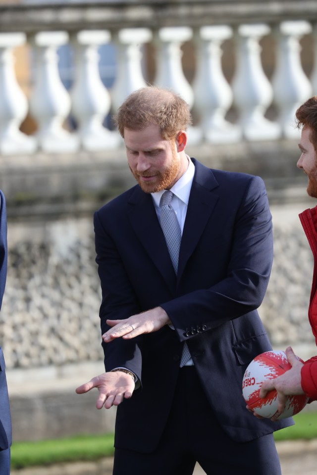 Harry mimes his rugby skills in the palace gardens