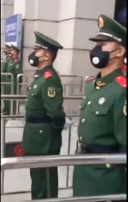 Authorities guard the train station in Wuhan while wearing masks