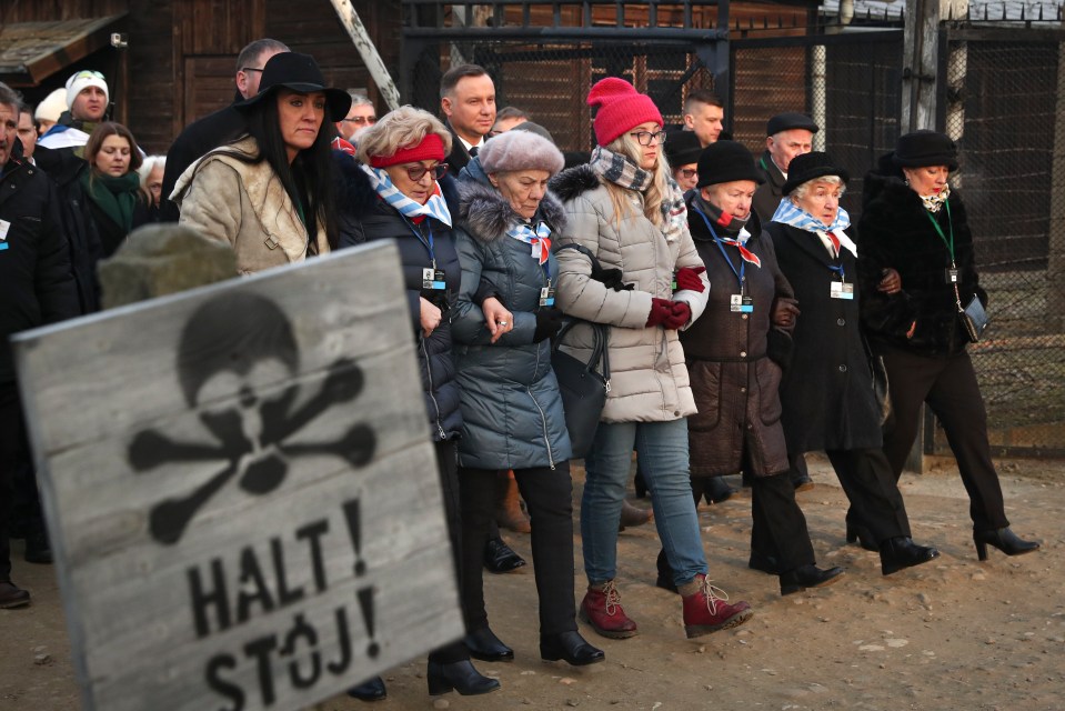 Poland's President Andrzej Duda walks along with survivors through the gates of the Auschwitz