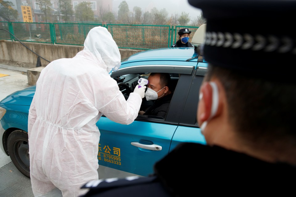  A medical worker in protective suit checks the body temperature of a car passenger at a checkpoint outside the city of Yueyang, Hunan Province, near the border to Hubei Province that is on lockdown