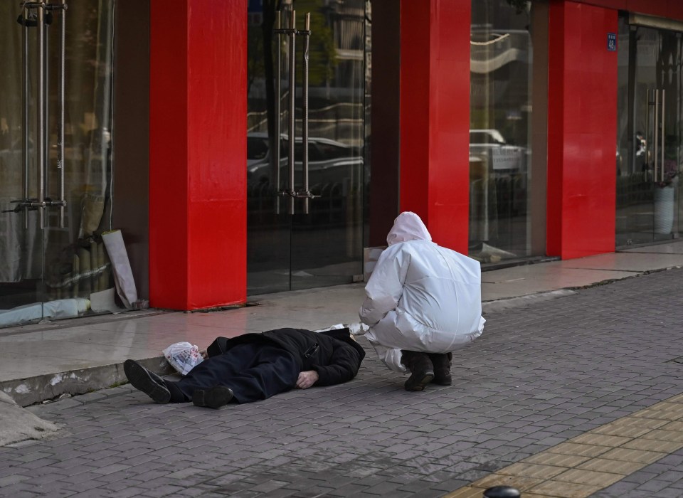 A medic in a hazmat suit with the body of the mask-wearing man in Wuhan 