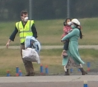  Families wearing face masks were led from the plane by staff at the RAF base