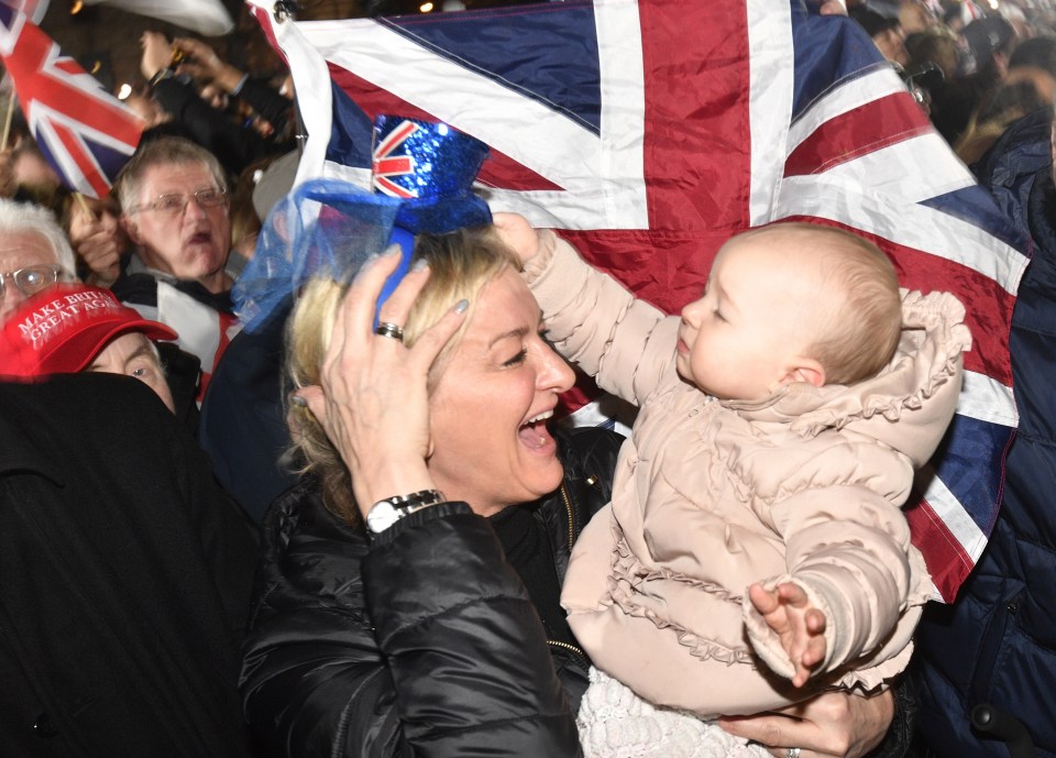  A woman hugs her baby at the Brexit rally in Parliament Square in front of a Union Jack flag