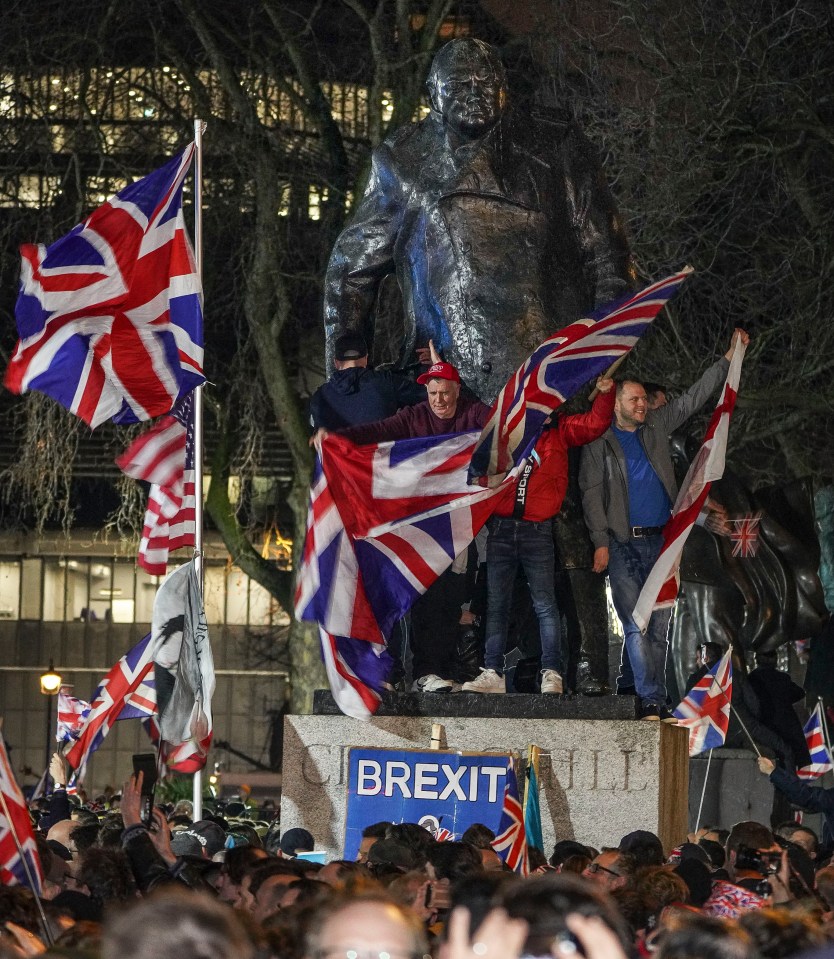  People climb on the statue of Winston Churchill with flags