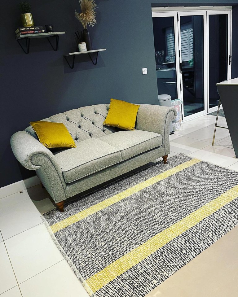  The space also has a grey sofa with yellow cushions on it