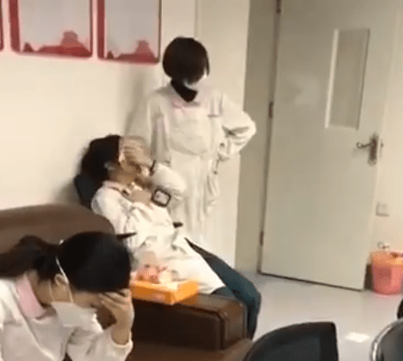  A colleague in a medical mask tries to comfort the woman as she wipes her tears with a tissue