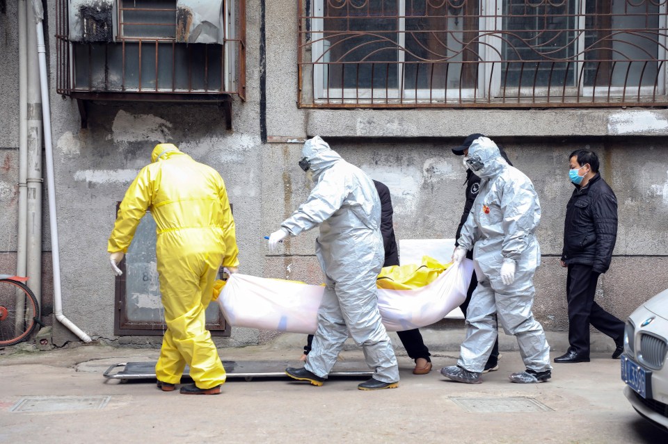  Emergency workers wearing hazmat suits removing the body of someone believed to have died from the virus in Wuhan