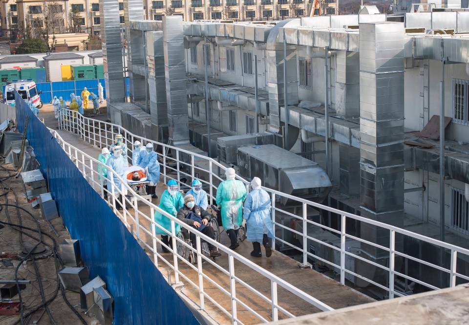 Medical workers in protective suits help transfer the first group of patients into the newly-completed Huoshenshan temporary field hospital in Wuhan