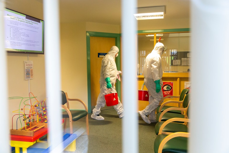 Men in hazmat suits clean the County Oak medical centre in Brighton