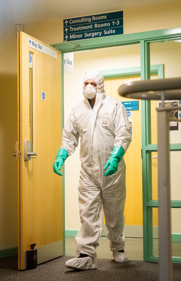 A worker in a hazmat suit cleans the County Oak medical centre in Brighton, East Sussex, after a staff member was diagnosed with coronavirus