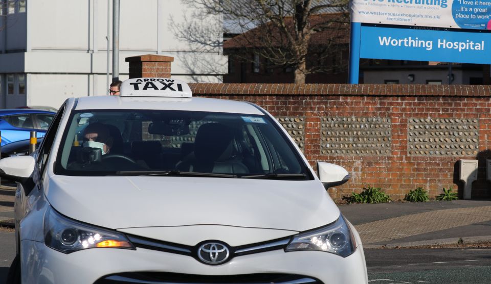  A taxi driver in a face mask pulls out of Worthing Hospital, where a doctor was confirmed as one of eight coronavirus carriers in the UK