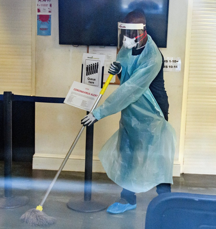 A man in a medical mask cleaning surfaces inside Ritchie Street Health Centre in Islington