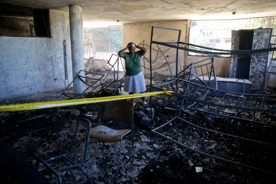  Staff worker Rose-Marie Louis holds her head amid the charred children's home