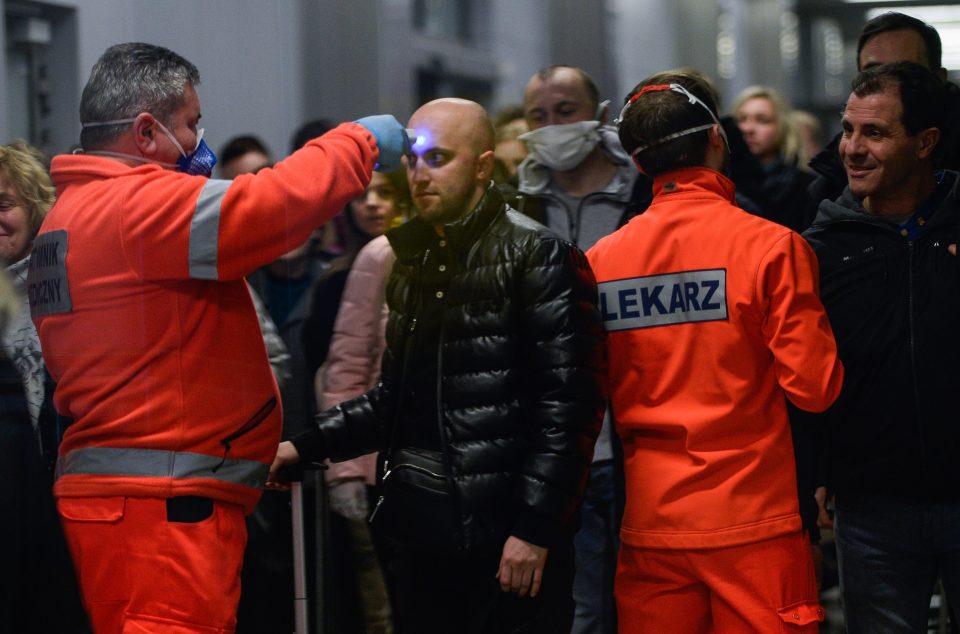  A health worker screens the temperature of a passenger arriving from Milan Bergamo to Krakow International Airport 