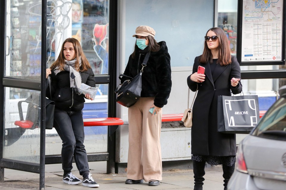 A woman wearing a surgical face mask as a precaution against coronavirus at a bus stop in Westminster