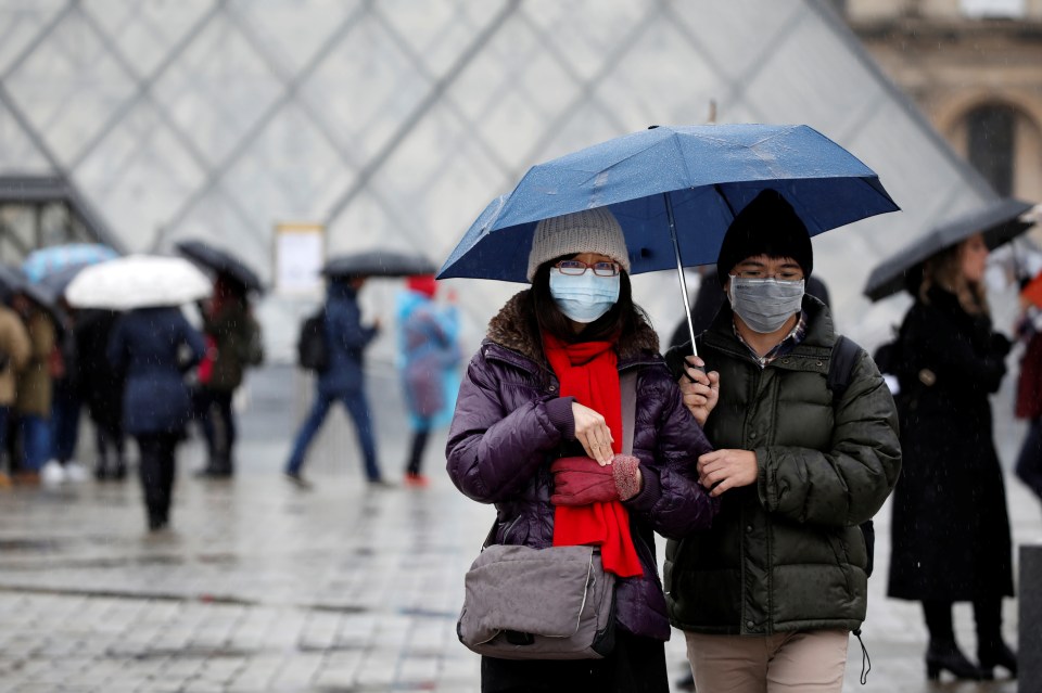 Tourists wearing masks walk away from the Louvre after the staff closed the museum