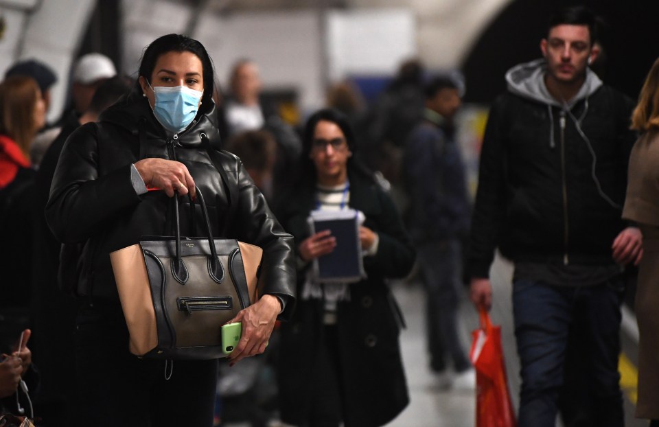 A woman wears a protective mask while waiting for a train