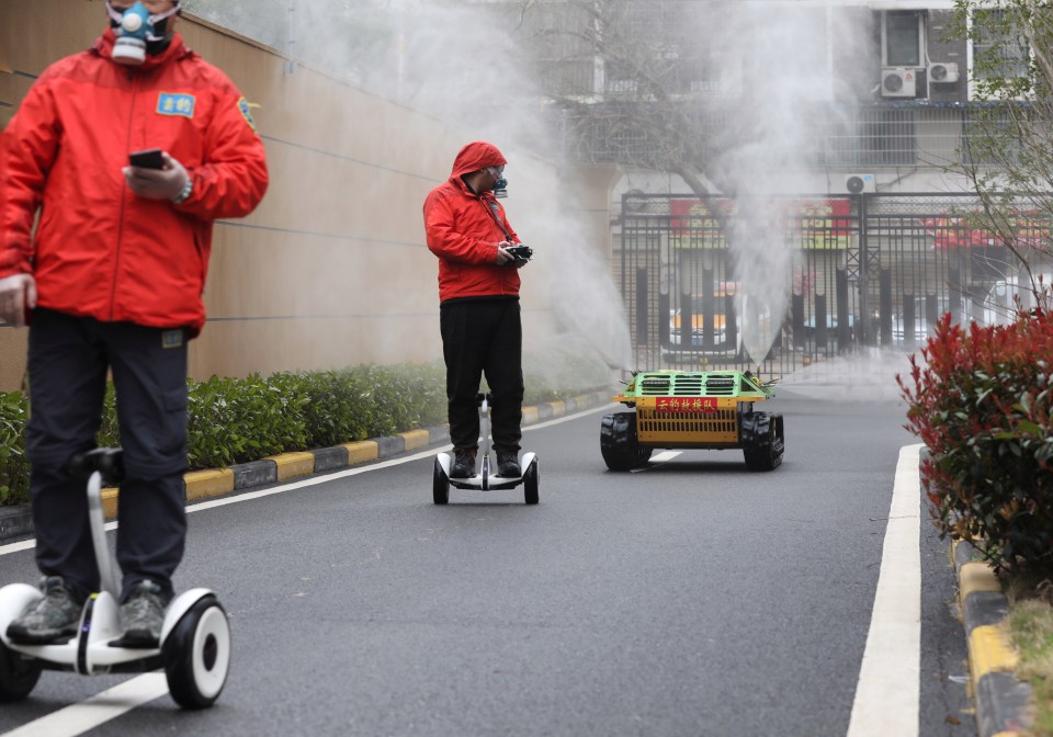 Workers use a robot to spray disinfectant in a residential area of Wuhan