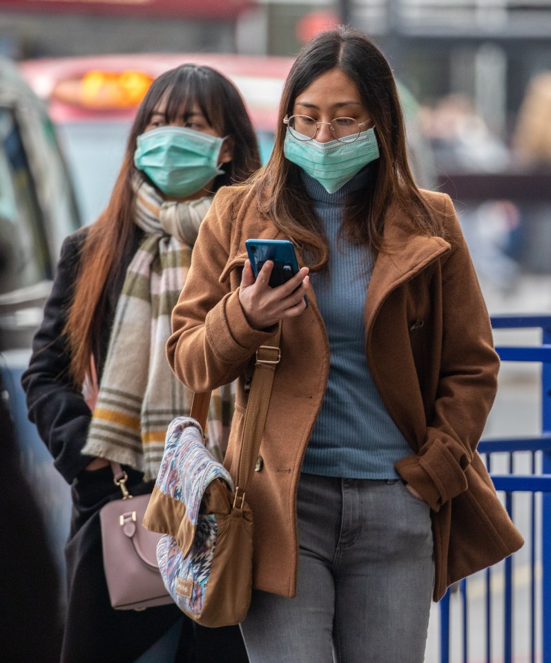  Two travellers walk past a taxi rank wearing masks in Westminster