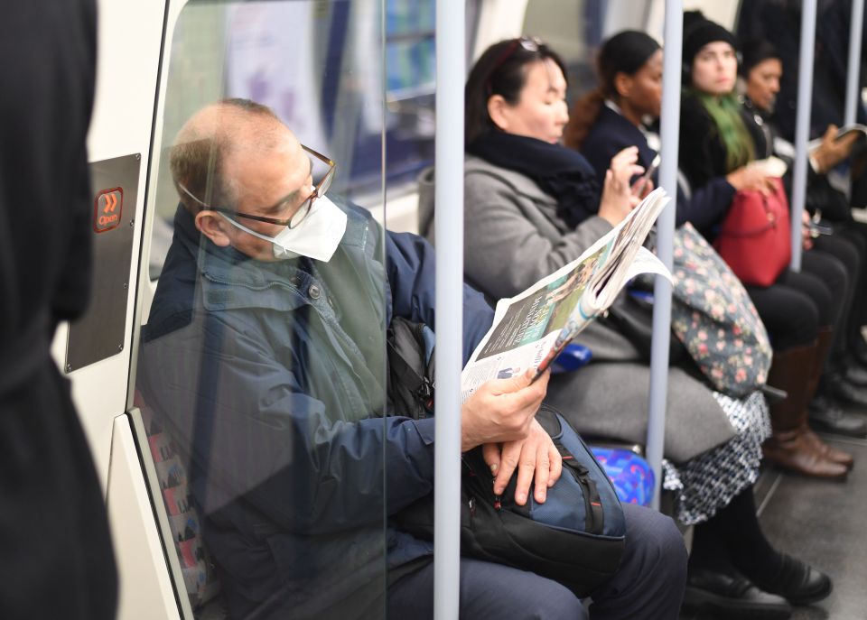  A man is seen reading a newspaper while travelling on the Tube