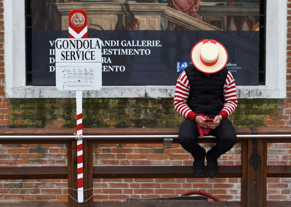  A Gondoliere checks his mobile phone while waiting for tourists in Venice