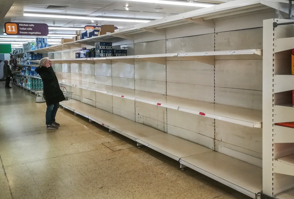 A shopper looks at empty toilet roll shelves in Sainsbury's in Cobham, Surrey