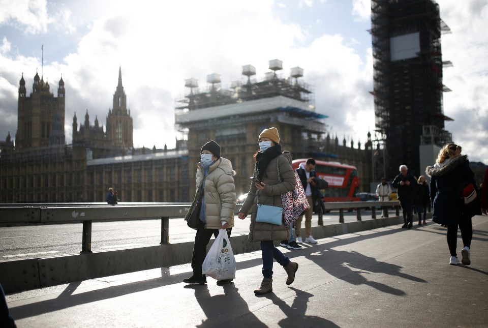  People in face masks walk past the Houses of Parliament today