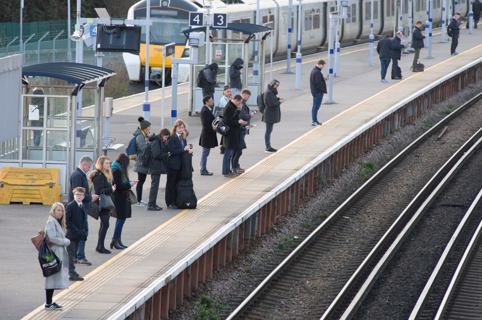  Commuters standing apart on a half empty train platform in Pettswood, Kent