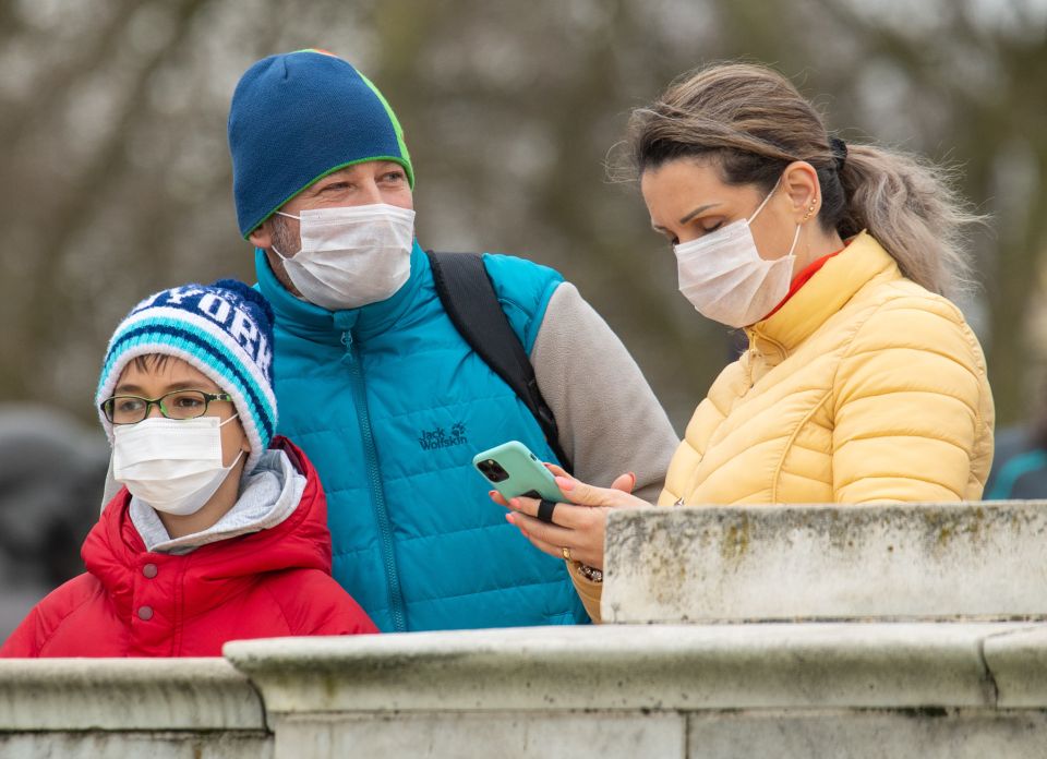  People wearing protective face masks watch the Changing of the Guard ceremony outside Buckingham Palace